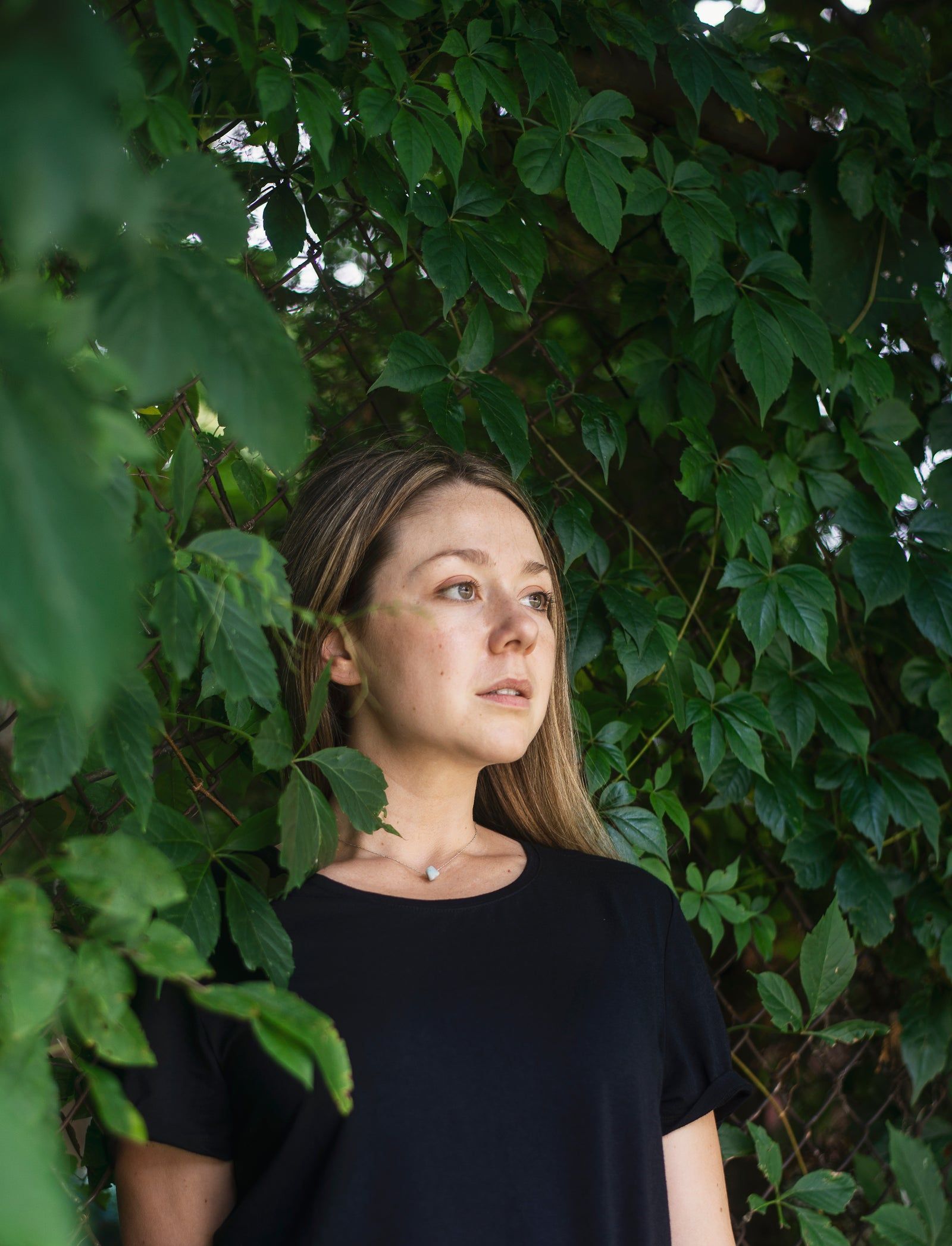 Femme en t-shirt noir entourée de vigne vierge
